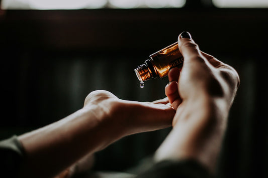 Hand holding an amber glass bottle of hair oil