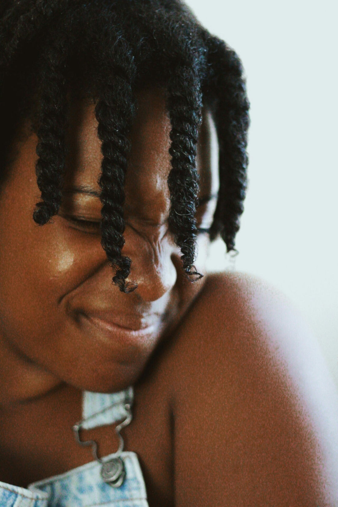 Black woman with natural hair standing by a white wall