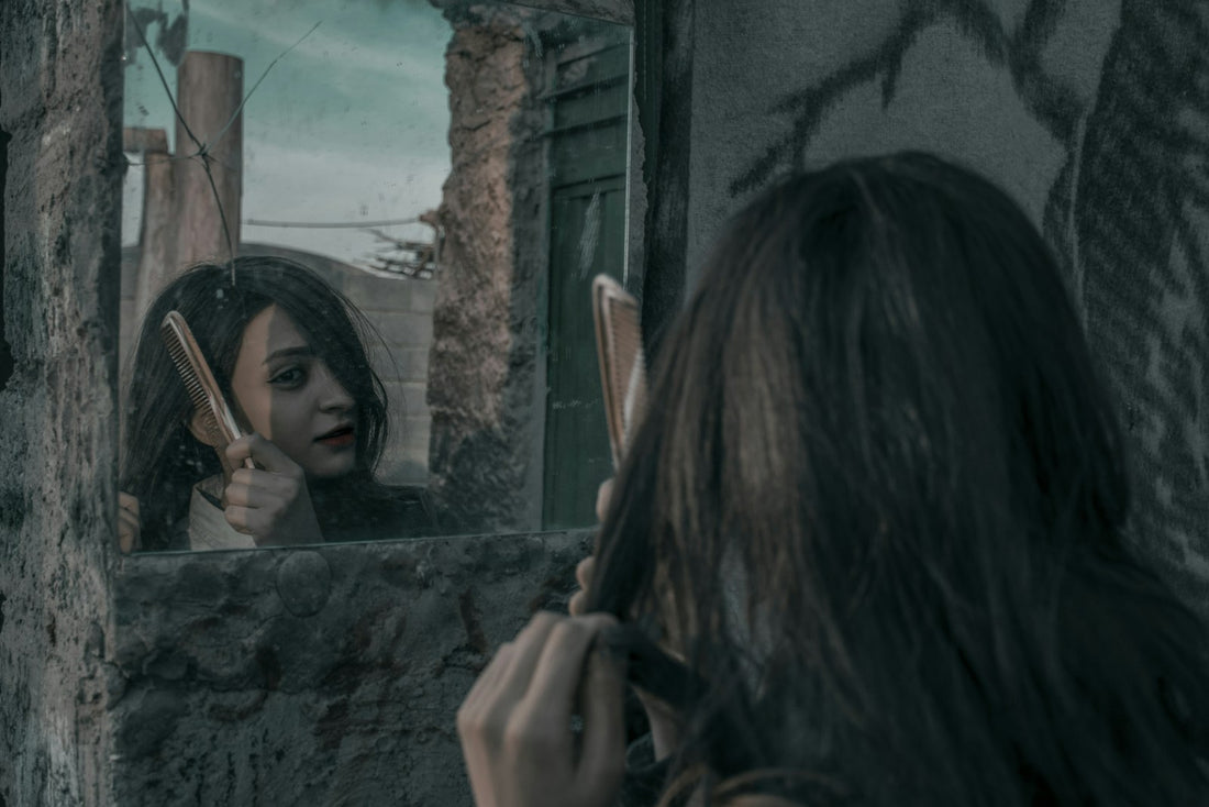 Woman combing her hair in front of a mirror