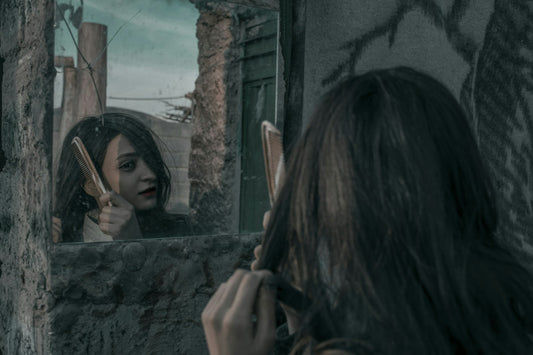Woman combing her hair in front of a mirror