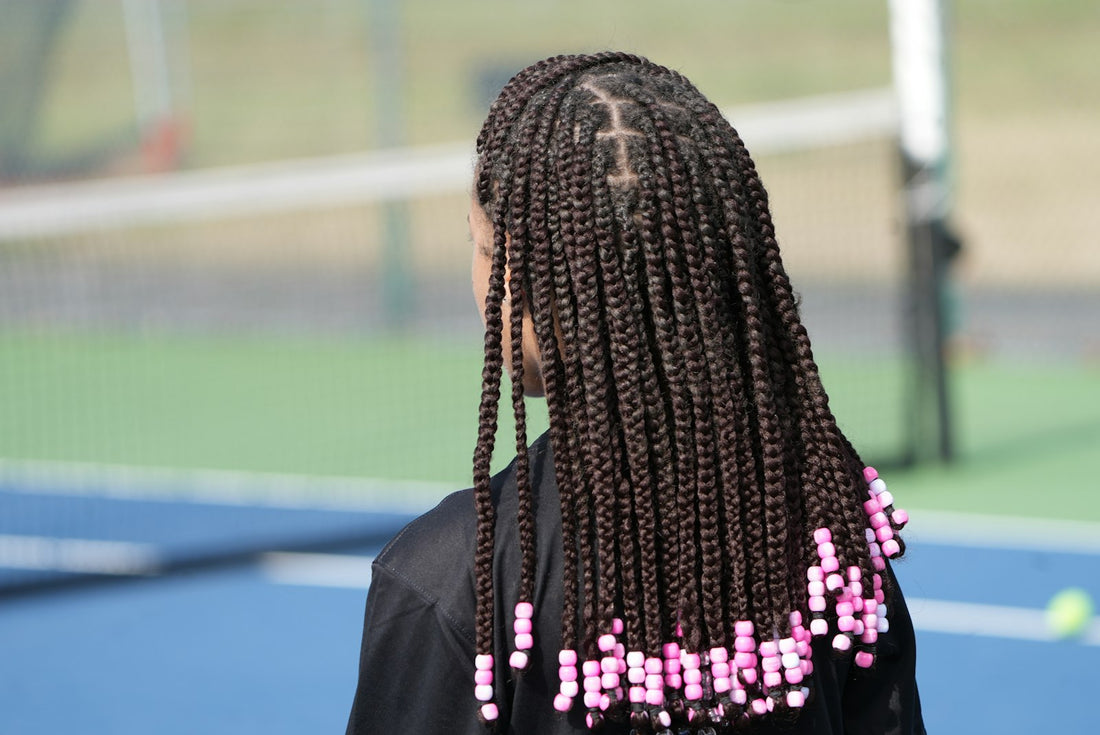 Black woman with long box braids decorated with grey beads