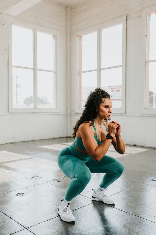 A woman doing squats in a gym to build her glutes and hips