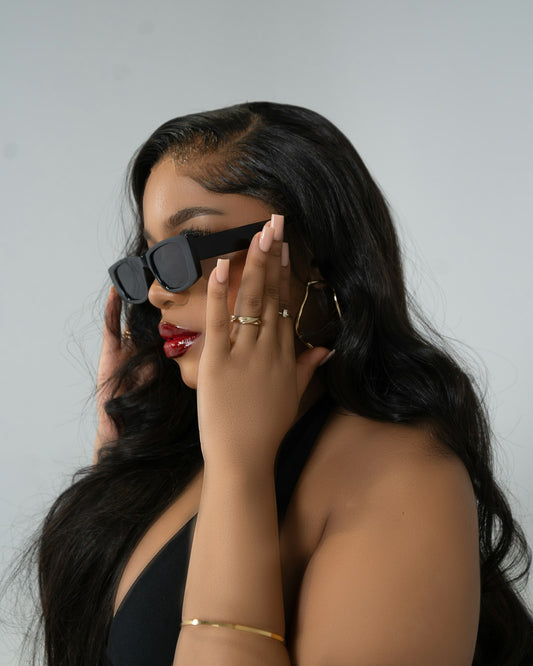Black woman wearing a sleek wig and red lipstick, holding sunglasses